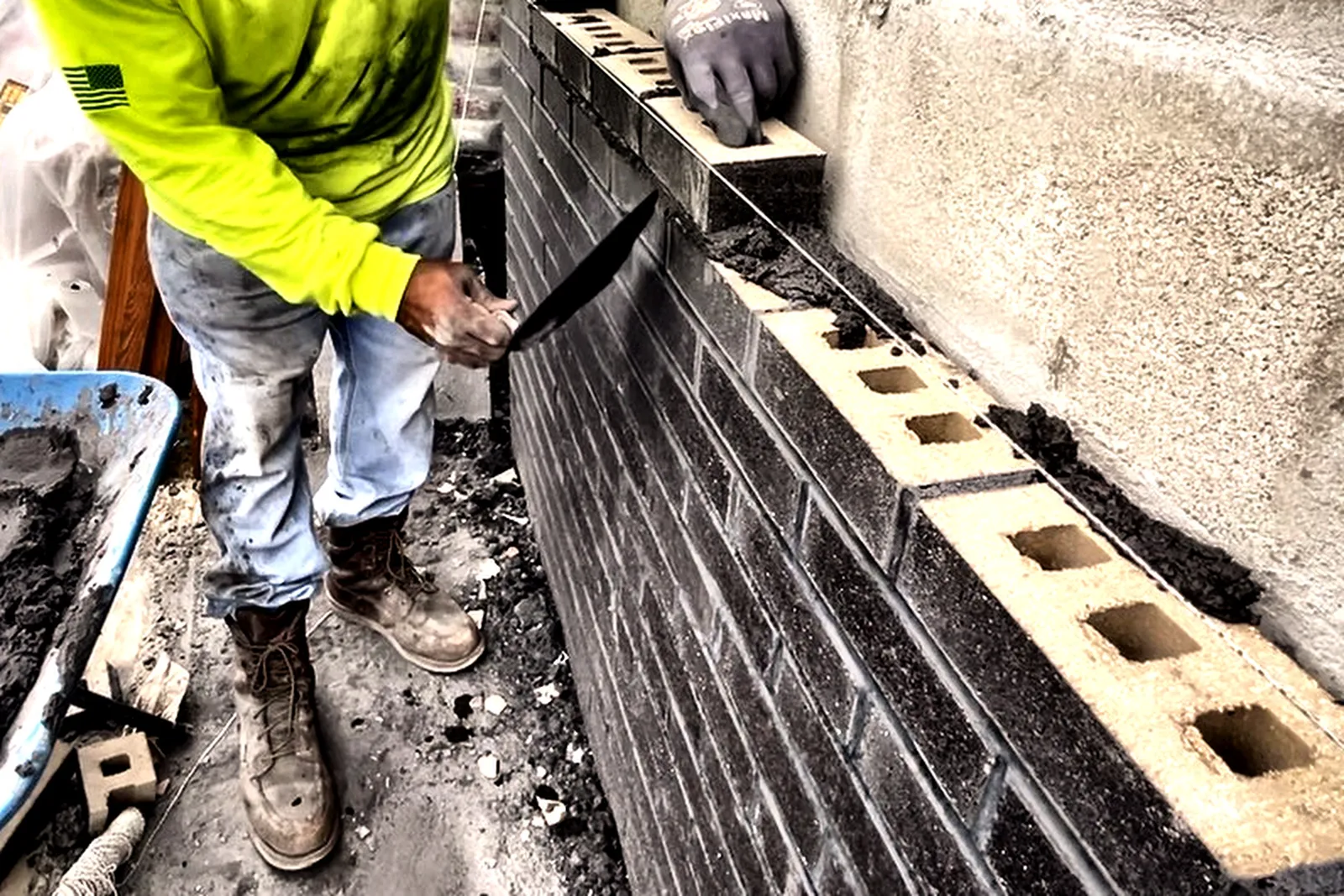 Mason setting dark brick veneer against new block