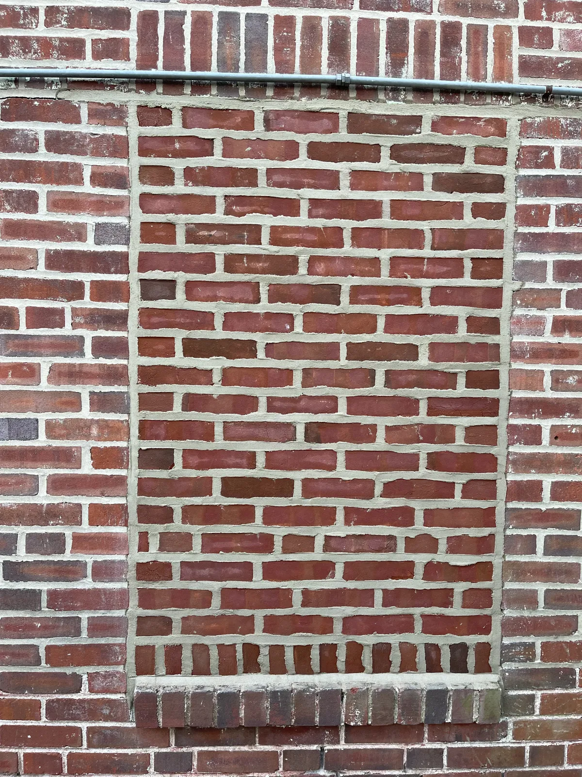After: Window opening infilled with brick and mortar matched to the existing wall